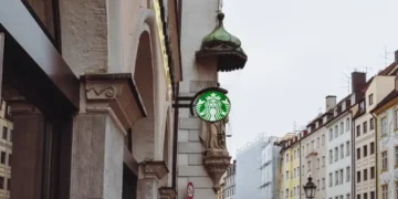 Starbucks siren sign stands before an Archangel Michael statue on Sendlinger Straße in Munich, Germany.