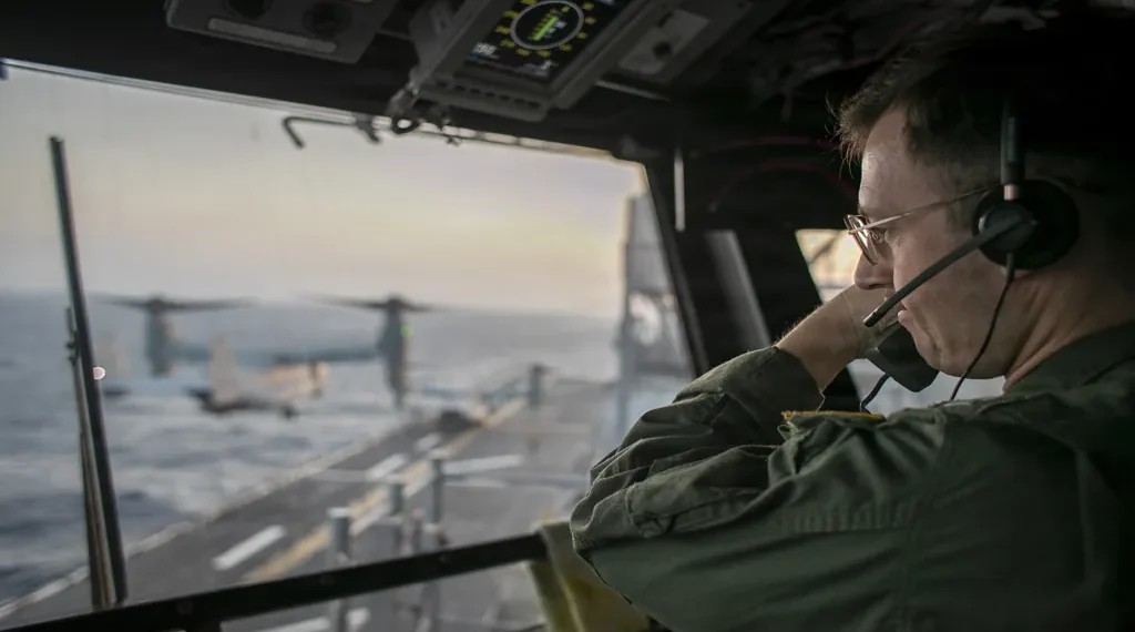 U.S. Navy officer oversees flight operations from USS Tripoli’s control tower as the amphibious assault ship sails in the Arabian Sea.