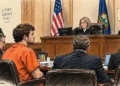 Vermont courtroom scene shows a defendant in orange seated before a judge, with attorneys and a law enforcement officer present.
