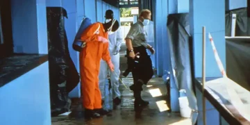 A photographer has the soles of their shoes sprayed with disinfectant after leaving an infected area during the 1995 Ebola outbreak in Kikwit, Zaire.