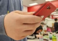 Teenager holding a red second-generation iPhone SE, photographed on May 22, 2024.
