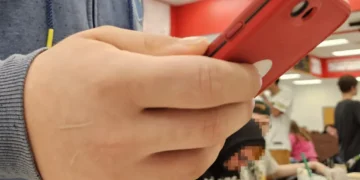 Teenager holding a red second-generation iPhone SE, photographed on May 22, 2024.