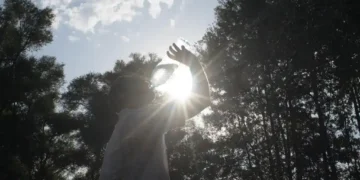 A man drinking water from a bottle outdoors on a sunny summer day