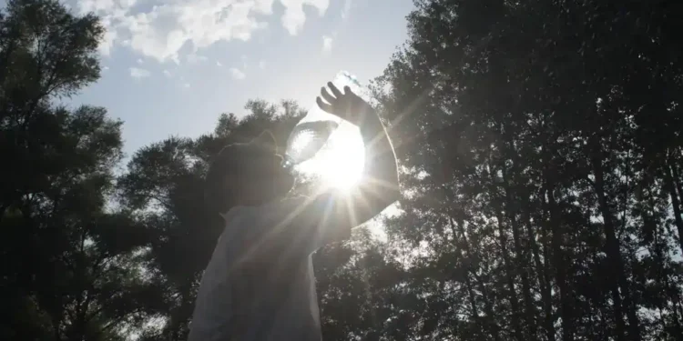 A man drinking water from a bottle outdoors on a sunny summer day