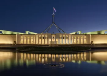 Australian Parliament House in Canberra photographed at blue hour, with the building illuminated against the evening sky.