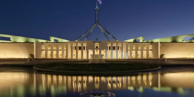 Australian Parliament House in Canberra photographed at blue hour, with the building illuminated against the evening sky.