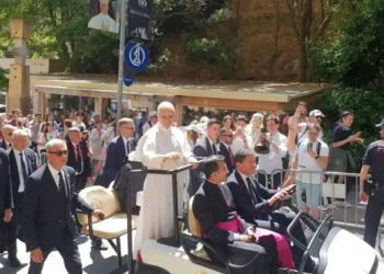 Pope Leo XIV raises his hand to greet pilgrims, volunteers and Mossos d'Esquadra officers at Montserrat Abbey in Spain.